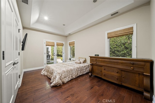 bedroom featuring access to outside, a tray ceiling, dark hardwood / wood-style floors, and french doors