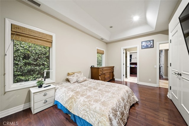 bedroom featuring a tray ceiling and dark hardwood / wood-style flooring