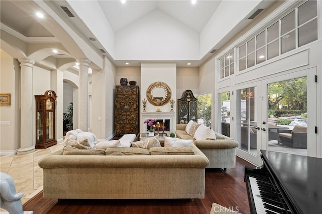 living room with high vaulted ceiling, decorative columns, dark hardwood / wood-style floors, and french doors