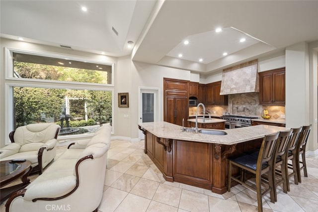 kitchen with appliances with stainless steel finishes, a breakfast bar, light stone countertops, a large island, and sink