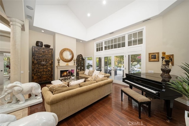 living room with dark wood-type flooring, ornate columns, high vaulted ceiling, and a healthy amount of sunlight