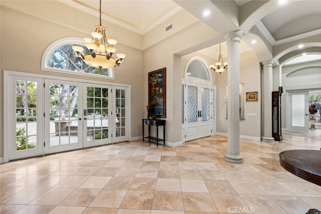 foyer entrance with ornate columns, a high ceiling, an inviting chandelier, french doors, and ornamental molding