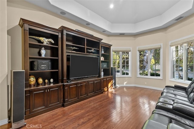 living room with a raised ceiling and hardwood / wood-style flooring