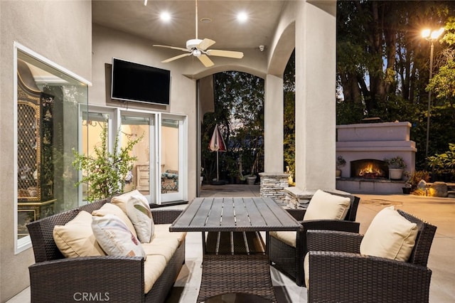 view of patio featuring ceiling fan and an outdoor living space with a fireplace