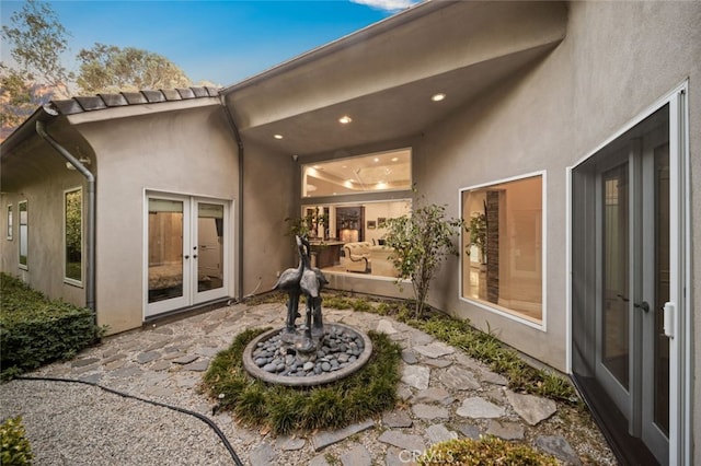 back house at dusk with french doors and a patio area