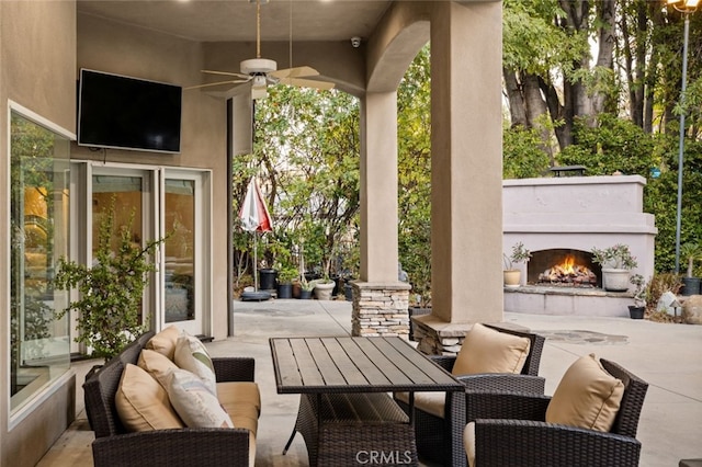 view of patio / terrace featuring ceiling fan and an outdoor living space with a fireplace