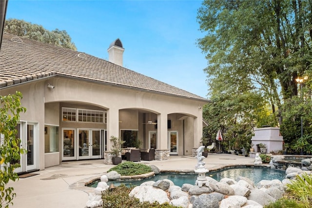 rear view of property with a patio, a pool with hot tub, and french doors