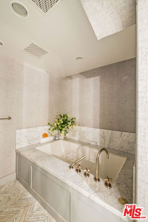 bathroom with parquet flooring and a bath