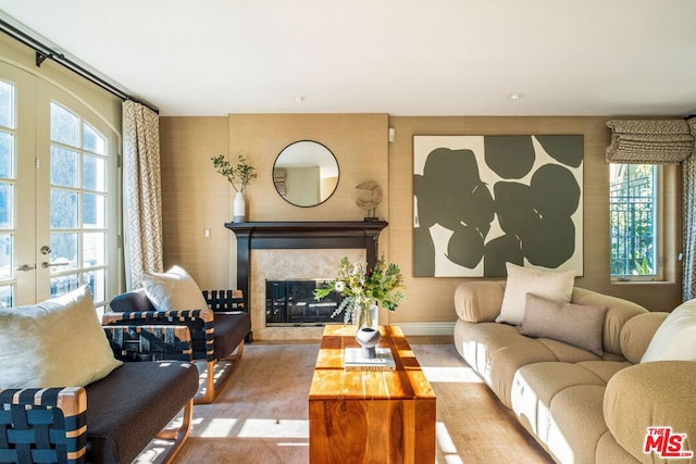 living room featuring light hardwood / wood-style flooring, a high end fireplace, and french doors