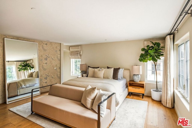 bedroom with multiple windows and light hardwood / wood-style floors