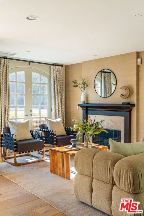 living room with a tiled fireplace, hardwood / wood-style floors, and french doors