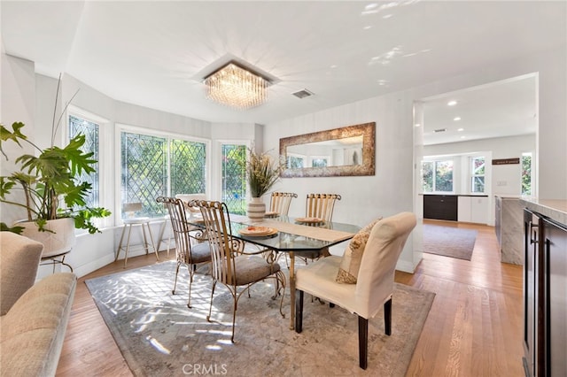 dining room featuring wine cooler, light wood-type flooring, and a chandelier