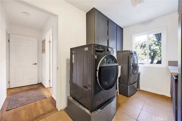 laundry room with washing machine and dryer, light tile patterned floors, and cabinets