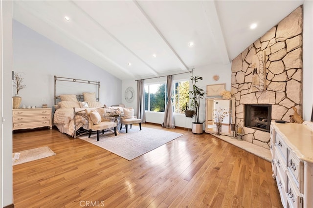 bedroom with lofted ceiling with beams, light hardwood / wood-style floors, and a fireplace