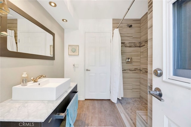 bathroom with walk in shower, vanity, and hardwood / wood-style flooring