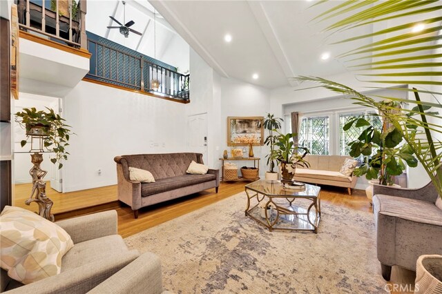 living room with high vaulted ceiling, wood-type flooring, ceiling fan, and beamed ceiling