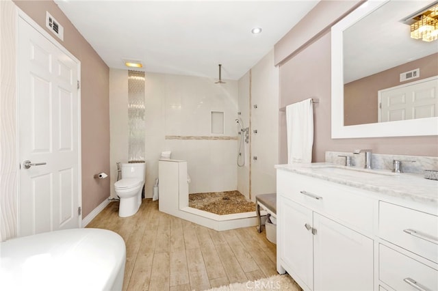 bathroom featuring vanity, toilet, hardwood / wood-style floors, and tiled shower