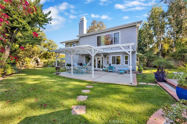 rear view of property with a pergola, a yard, and a patio area