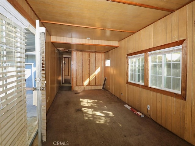 carpeted spare room with wood walls and wood ceiling