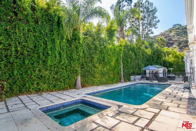 view of pool with an in ground hot tub and a patio area