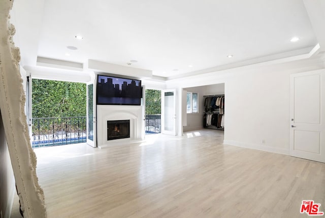 unfurnished living room with a tray ceiling and light hardwood / wood-style flooring