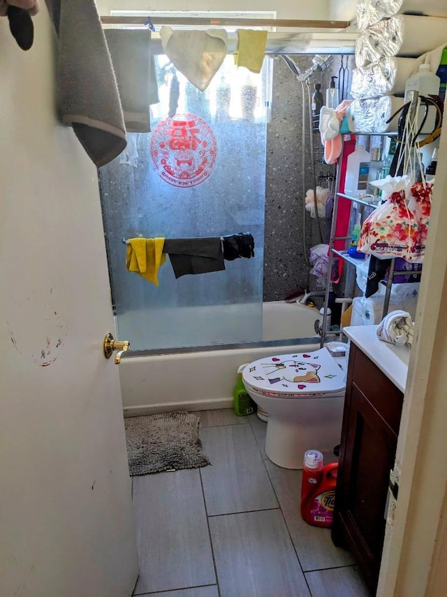 full bathroom with combined bath / shower with glass door, vanity, and toilet