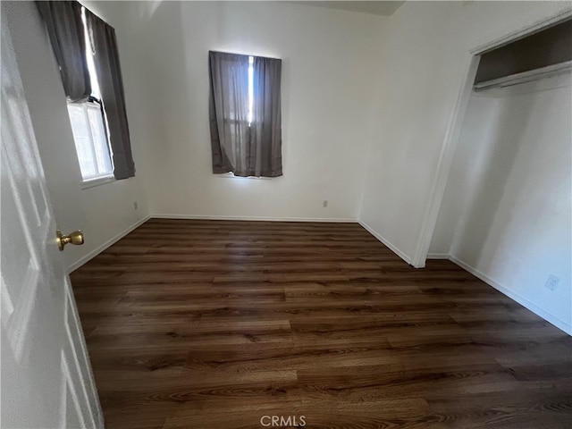 unfurnished bedroom with a closet and dark wood-type flooring