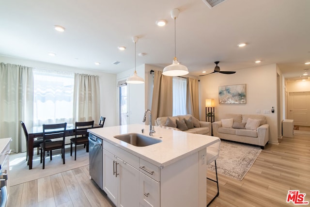 kitchen featuring pendant lighting, white cabinets, sink, stainless steel dishwasher, and light wood-type flooring