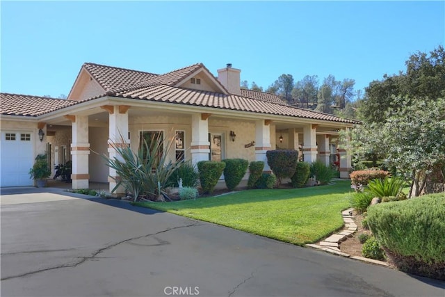 view of front of house featuring stucco siding, a tile roof, a front lawn, and an attached garage
