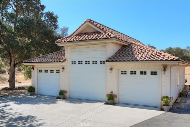 exterior space featuring a tile roof, a garage, and stucco siding