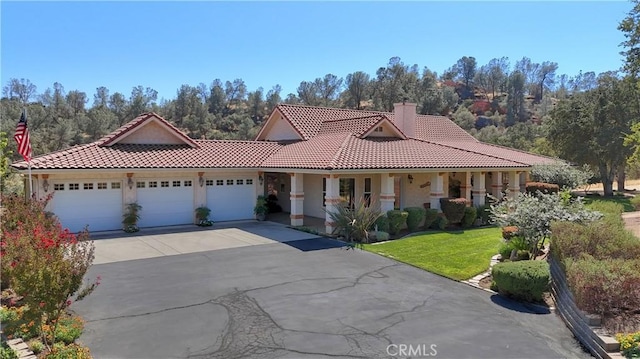 view of front of home featuring a chimney, an attached garage, a tiled roof, and aphalt driveway