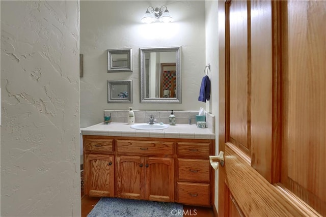 bathroom with a textured wall and vanity