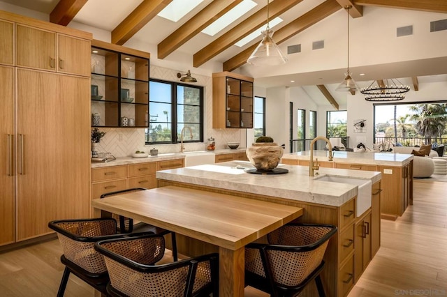 kitchen featuring a skylight, a center island with sink, plenty of natural light, and high vaulted ceiling