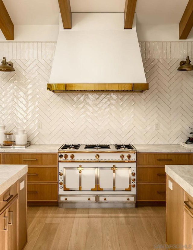 kitchen with beam ceiling, light hardwood / wood-style floors, decorative backsplash, and double oven range