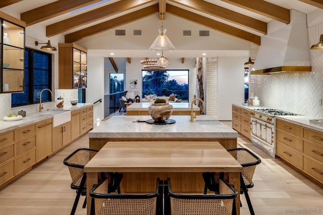 dining space featuring beam ceiling, light hardwood / wood-style floors, and sink