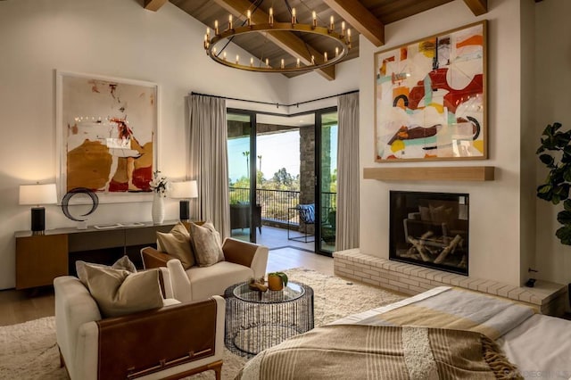 living room featuring vaulted ceiling with beams, wood ceiling, hardwood / wood-style flooring, an inviting chandelier, and a fireplace