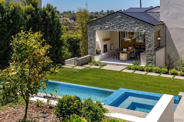 view of swimming pool with exterior fireplace, a lawn, an in ground hot tub, and a patio area