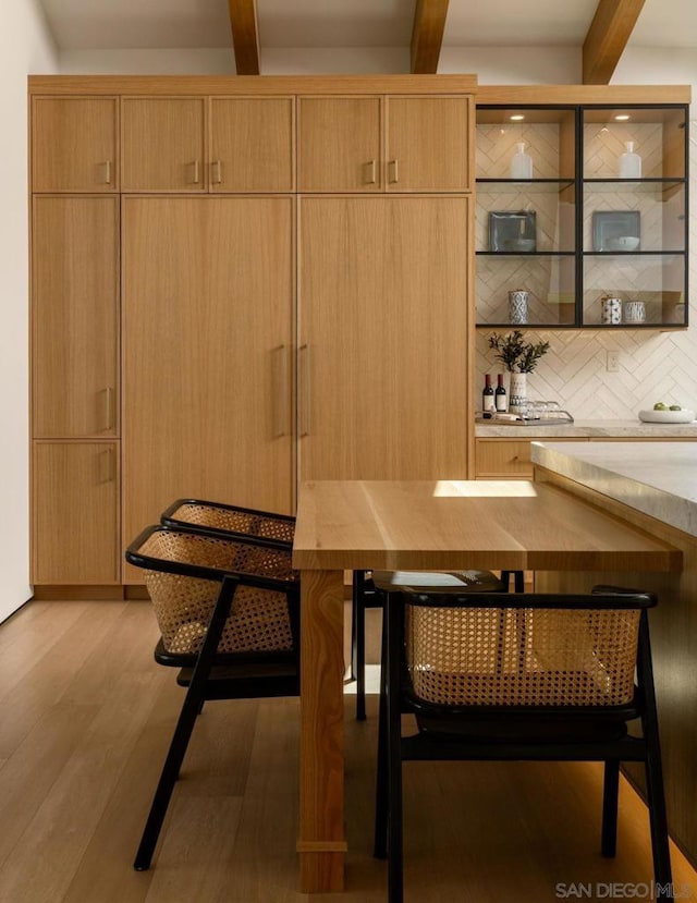 dining space featuring light hardwood / wood-style flooring and beam ceiling