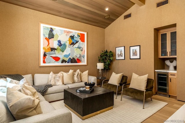 living room featuring bar area, wine cooler, light wood-type flooring, and high vaulted ceiling