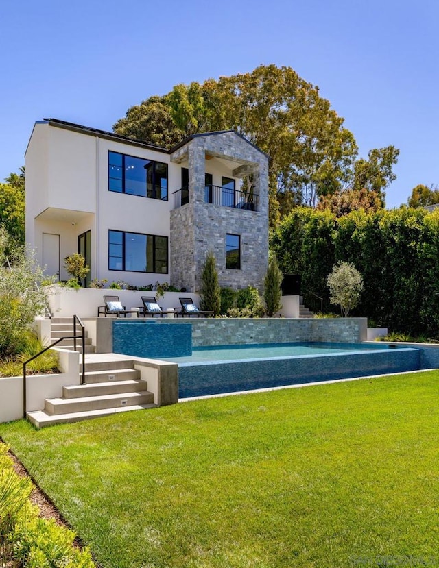 rear view of house featuring a balcony, a yard, and a patio area