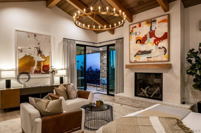 living room featuring beamed ceiling, wood ceiling, a brick fireplace, an inviting chandelier, and hardwood / wood-style floors