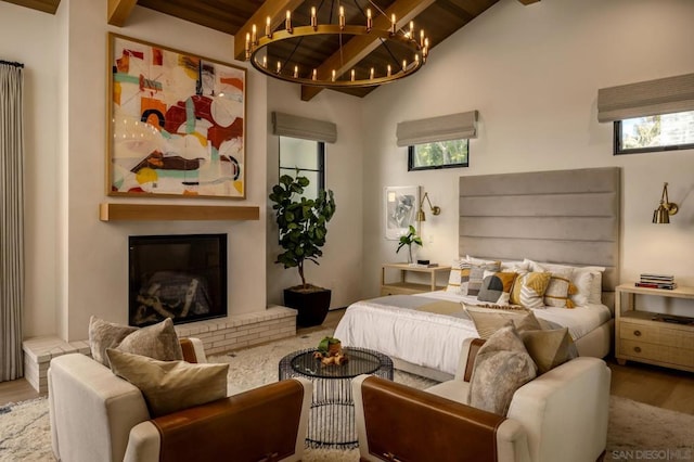 bedroom with high vaulted ceiling, a fireplace, wooden ceiling, an inviting chandelier, and hardwood / wood-style floors