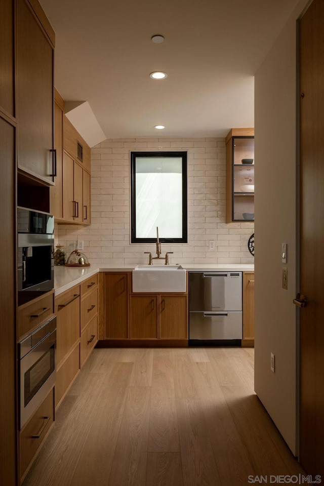 kitchen featuring light wood-type flooring, backsplash, appliances with stainless steel finishes, and sink