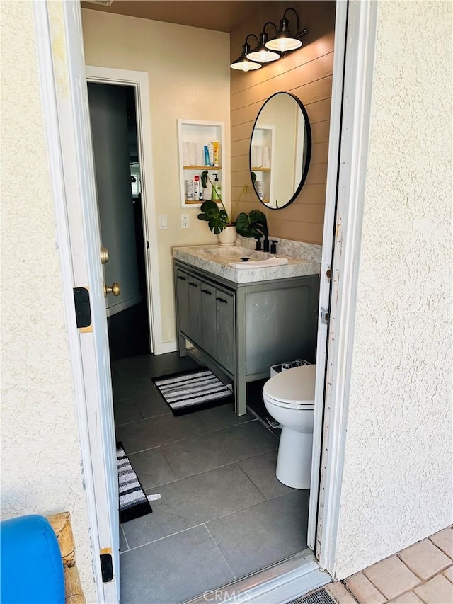 bathroom with toilet, vanity, and tile patterned flooring