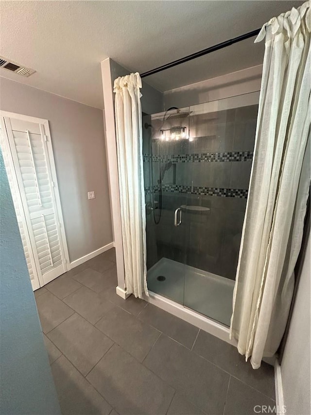 bathroom with a textured ceiling, tile patterned floors, and walk in shower