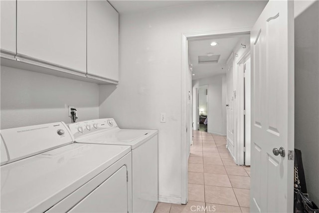 laundry room with light tile patterned flooring, washer and dryer, and cabinets