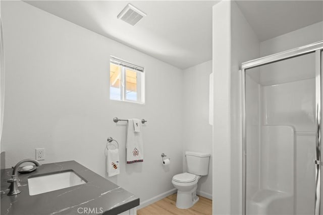 bathroom featuring toilet, hardwood / wood-style floors, an enclosed shower, and vanity