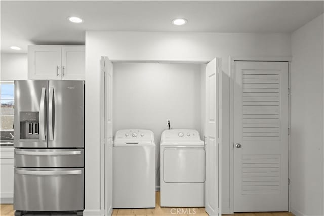 clothes washing area featuring light hardwood / wood-style flooring and washing machine and clothes dryer