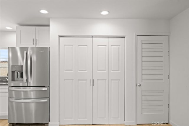 kitchen with stainless steel refrigerator with ice dispenser and white cabinets