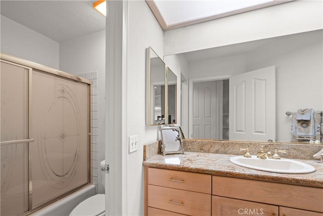 full bathroom featuring combined bath / shower with glass door, vanity, and toilet